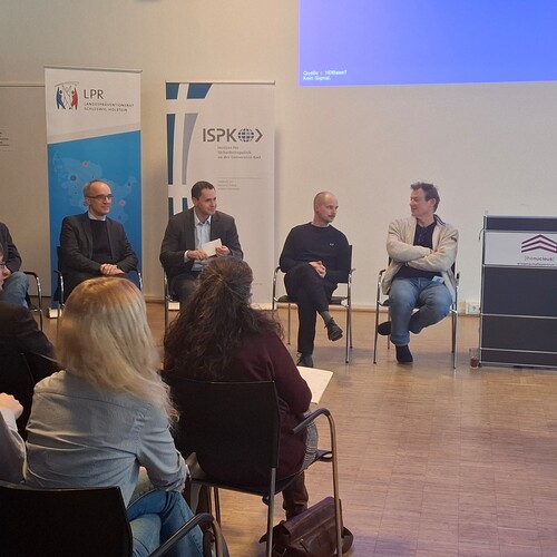 Podiumsdiskussion mit vier Referenten und einem Moderator zu Desinformation